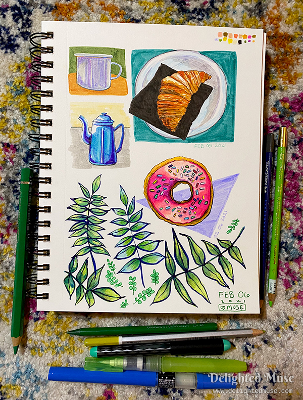 Sketchbook page filled with drawings of a donut, leaves, a teapot, a croissant, and a mug. Watercolor pencils and ink pens are laid next to the sketchbook