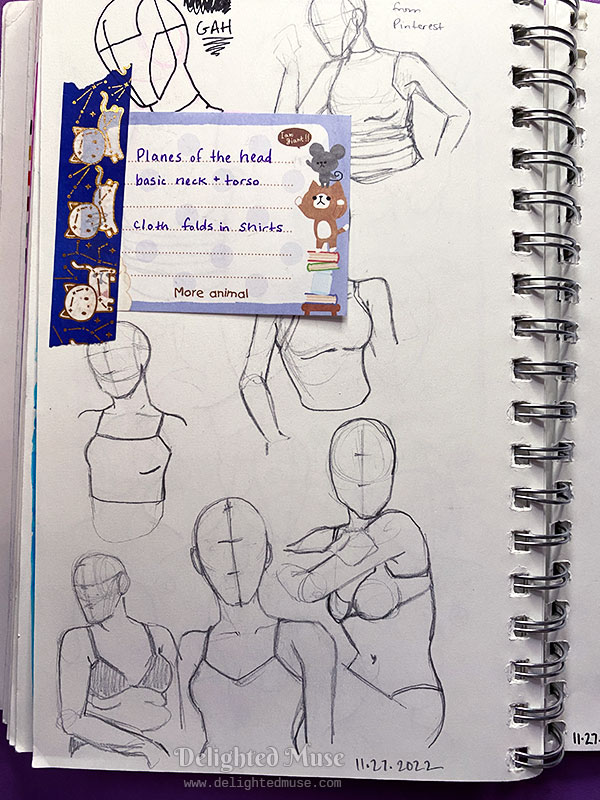 Sketchbook page with rough sketches of figures, with a washi-taped in note with study goals of planes of the head, basic neck and torso, and cloth folds in shirts.
