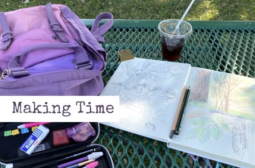 Photo of a green, metal picnic table. Ontop of the table is a an open sketchbook with drawings of trees, an plastic cup of iced coffee, a purple backpack, and a pencil case with art pencils and erasers.